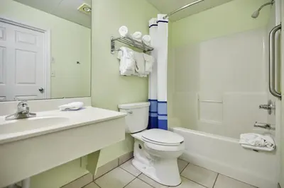 a bathroom with a toilet and a sink and a tub at Palmetto Beachfront Hotel, a By The Sea Resort in Panama City Beach