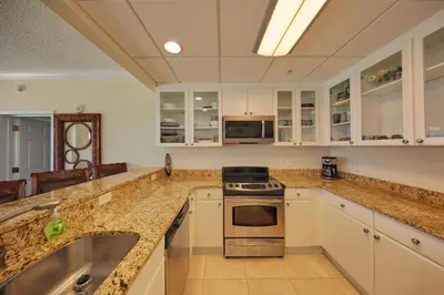 a kitchen with white cabinets and granite counter tops at Palmetto Beachfront Hotel, a By The Sea Resort in Panama City Beach