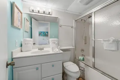 a bathroom with a sink and a toilet and a mirror at Sugar Beach C36 in Panama City Beach