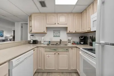 a kitchen with white cabinets and white appliances at Sugar Beach C36 in Panama City Beach