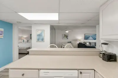 a kitchen with a counter top and a living room at Sugar Beach C36 in Panama City Beach