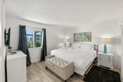 a white bedroom with a bed and a chair at Sugar Beach C36 in Panama City Beach