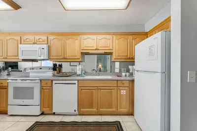 a kitchen with wooden cabinets and white appliances at The Summit 1032 in Panama City Beach