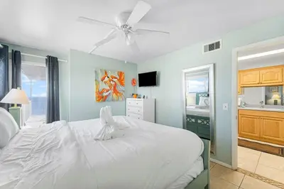 a bedroom with a white bed with a ceiling fan at The Summit 1032 in Panama City Beach