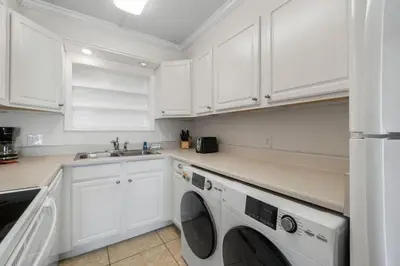 a kitchen with white cabinets and a washer and dryer at The Summit 321 in Panama City Beach