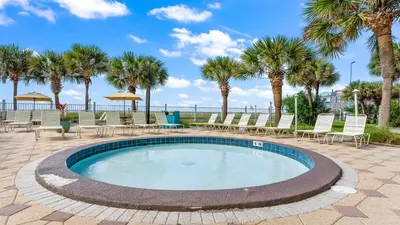 a swimming pool with chairs and palm trees at The Summit 321 in Panama City Beach