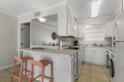 a kitchen with white cabinets and a counter with two stools at The Summit 321 in Panama City Beach