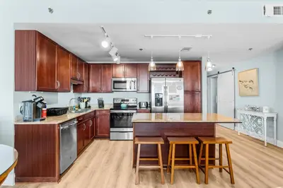 a kitchen with wooden cabinets and a island with bar stools at Stunning 4BD! Oceanview! Free Beach Chair Service! Sleeps 10! By Dolce Vita Getaways in Panama City Beach