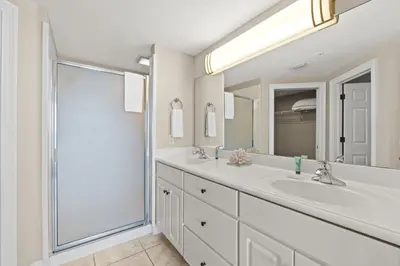 a white bathroom with two sinks and a shower at Treasure Island #1203 by Book That Condo in Panama City Beach