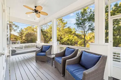 a screened porch with chairs and a ceiling fan at Greenway Loop by 30A Escapes in Rosemary Beach