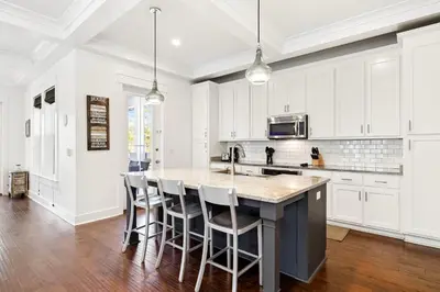 a kitchen with white cabinets and a island with bar stools at Greenway Loop by 30A Escapes in Rosemary Beach