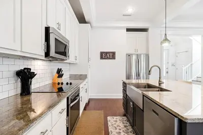 a kitchen with white cabinets and a sink at Greenway Loop by 30A Escapes in Rosemary Beach