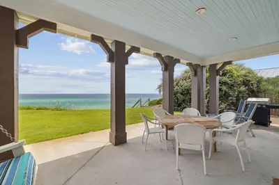 a porch with a table and chairs and the ocean at Always On My Mind by 30A Escapes in Seacrest