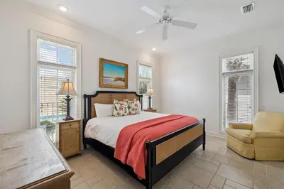 a bedroom with a bed and a chair and windows at Always On My Mind by 30A Escapes in Seacrest