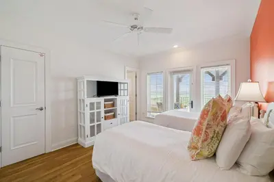a white bedroom with two beds and a tv at Always On My Mind by 30A Escapes in Seacrest