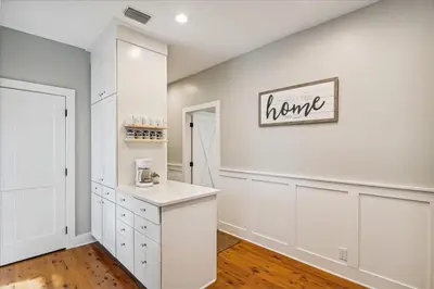 a kitchen with white cabinets and a sign that reads home at Sans Souci by 30A Escapes in Seacrest