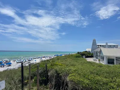 a beach with people sitting on the sand and the ocean at Sans Souci by 30A Escapes in Seacrest