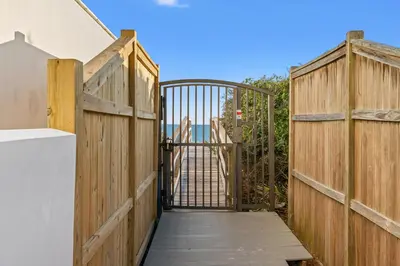 a wooden gate with a wooden walkway leading to a door at Sans Souci by 30A Escapes in Seacrest