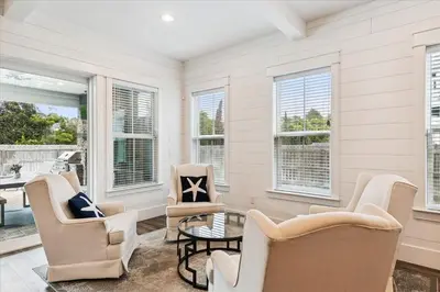 a living room with chairs and a table and windows at Family Tradition by 30A Escapes in Seacrest