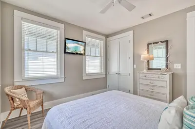 a bedroom with a bed and a chair and windows at Sandy Haven by 30A Escapes in Rosemary Beach