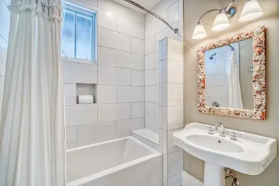 a white bathroom with a sink and a tub and a mirror at Sandy Haven by 30A Escapes in Rosemary Beach