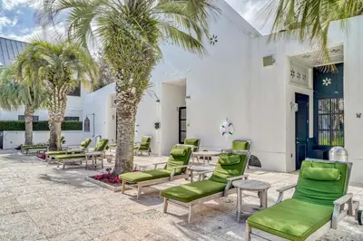 a patio with green chairs and palm trees at Sandy Haven by 30A Escapes in Rosemary Beach
