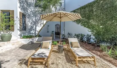 a patio with two chairs and an umbrella at Pappas Cottage by 30A Escapes in Rosemary Beach
