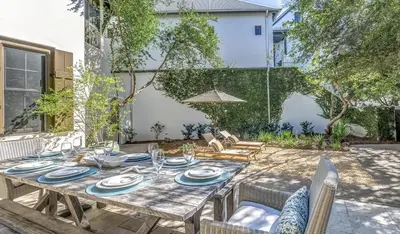 a wooden table with plates and glasses on a patio at Pappas Cottage by 30A Escapes in Rosemary Beach