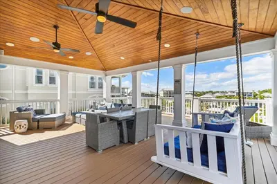 a porch with a swing and furniture on a deck at At Ease by 30A Escapes in Rosemary Beach