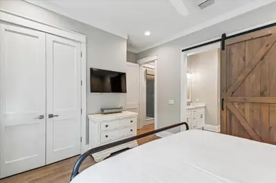 a bedroom with a bed and a tv and a sliding door at At Ease by 30A Escapes in Rosemary Beach