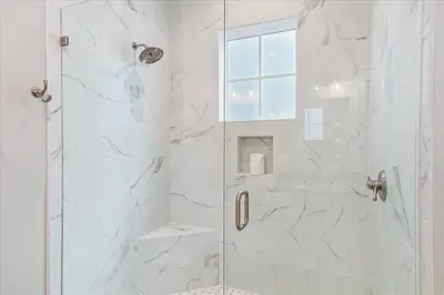 a white bathroom with a shower with a glass door at At Ease by 30A Escapes in Rosemary Beach