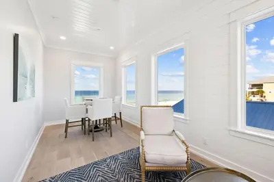 a dining room with a table and chairs and windows at Sea Castle by 30A Escapes in Sunnyside