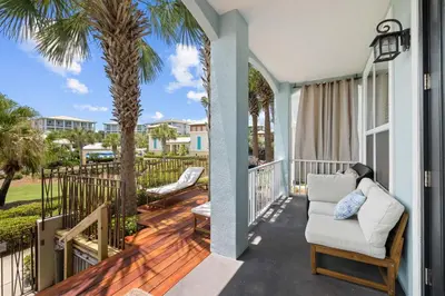 a porch with a chair and palm trees at Emerald Escape by 30A Escapes in Rosemary Beach