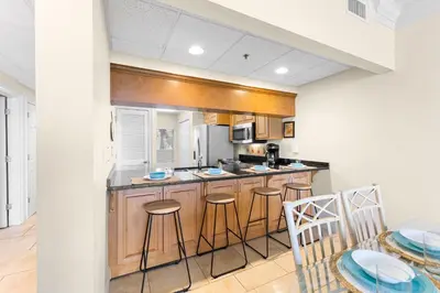 a kitchen with wooden cabinets and a table and chairs at HP 15E Gulf Front Condo by 30A Escapes in Rosemary Beach