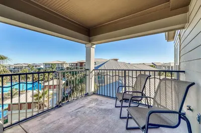 a balcony with two chairs and a pool at Happy Place by 30A Escapes in Rosemary Beach