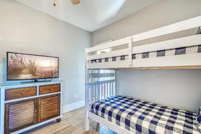 a bedroom with two bunk beds and a tv at Happy Place by 30A Escapes in Rosemary Beach