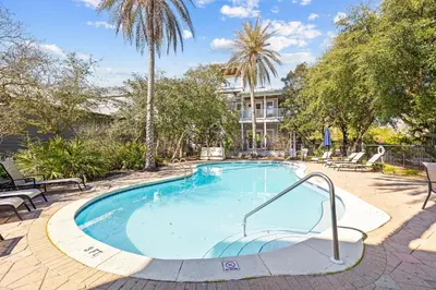 a swimming pool with a palm tree and a building at Sand Pointe by 30A Escapes in Inlet Beach