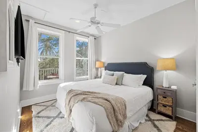 a white bedroom with a bed and two windows at Sand Pointe by 30A Escapes in Inlet Beach