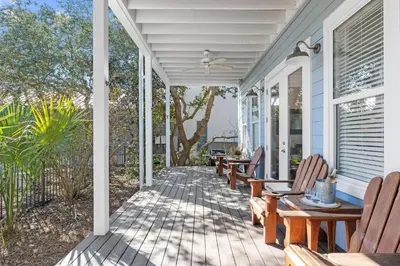 a porch with chairs and tables on a house at Sand Pointe by 30A Escapes in Inlet Beach
