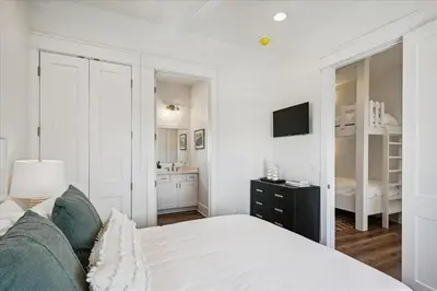a white bedroom with a bed and a bathroom at Sea Ya Soon by 30A Escapes in Rosemary Beach