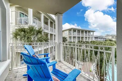 a pair of blue chairs on a balcony with condos at Poolside Paradise by 30A Escapes in Rosemary Beach
