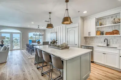 a kitchen with white cabinets and a large island with bar stools at Poolside Paradise by 30A Escapes in Rosemary Beach