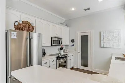 a kitchen with white cabinets and a stainless steel refrigerator at Endless Summer Escape by 30A Escapes in Rosemary Beach