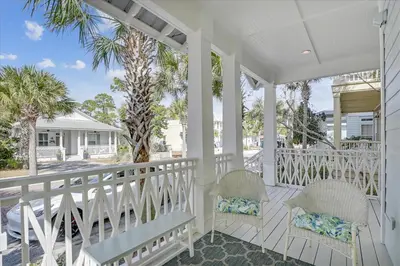 a white porch with two chairs and a palm tree at Endless Summer Escape by 30A Escapes in Rosemary Beach