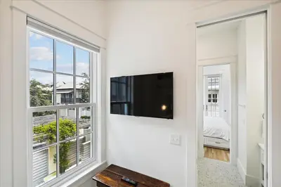 a living room with a large window and a flat screen tv at Tuscan Blue by 30A Escapes in Rosemary Beach