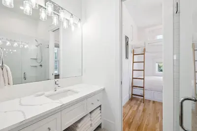 a white bathroom with a sink and a mirror at Tuscan Blue by 30A Escapes in Rosemary Beach