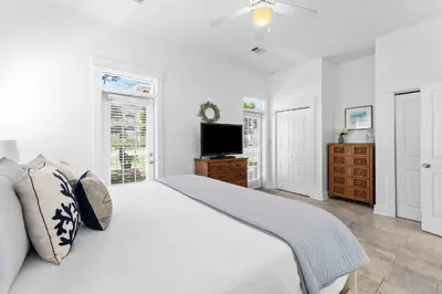 a white bedroom with a bed and a television at Hidden Gem #6 by 30A Escapes in Seacrest