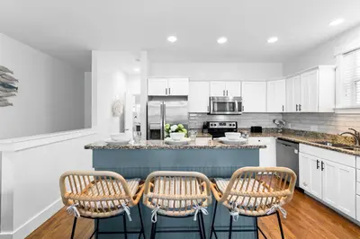 a kitchen with white cabinets and a counter with chairs at Hidden Gem #6 by 30A Escapes in Seacrest