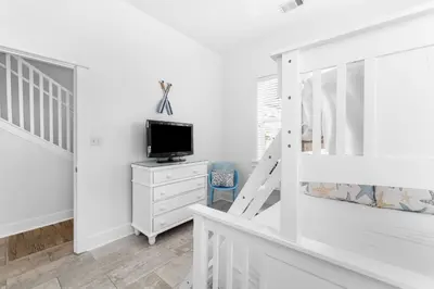 a white bedroom with a tv on a dresser and a staircase at Hidden Gem #6 by 30A Escapes in Seacrest
