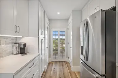 a kitchen with white cabinets and a refrigerator at HP 45W What the Heck by 30A Escapes in Rosemary Beach
